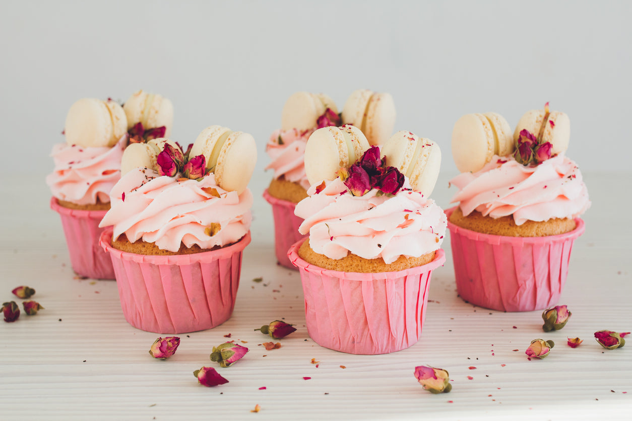 Essbare Rosenknospen auf Cupcakes mit pinker Sahne.
